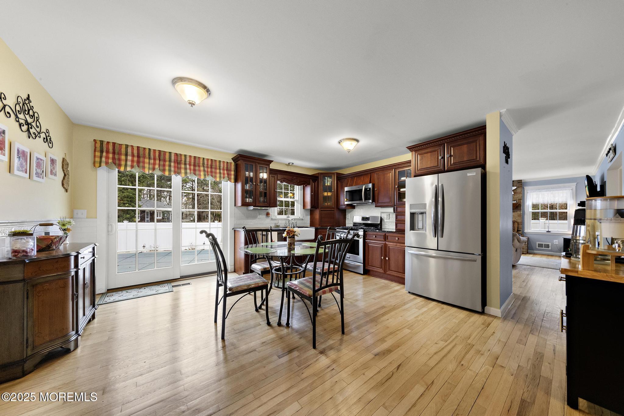 69 Chestnut Court Brick, NJ 08723 - Photo 7 of 23 a kitchen with stainless steel appliances a refrigerator a stove a dining table and chairs with wooden floor