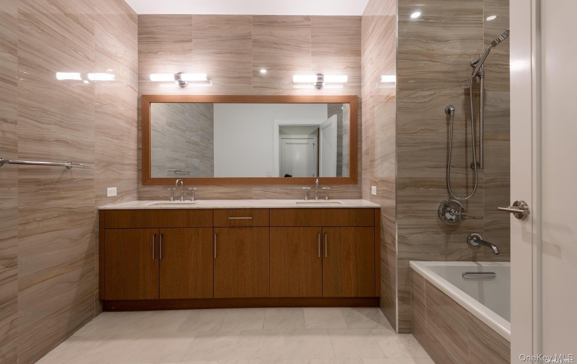 100 Garvies Point Road, Unit 1014 Glen Cove, NY 11542 - Photo 10 of 27 a bathroom with a bathtub a double vanity sink and mirror
