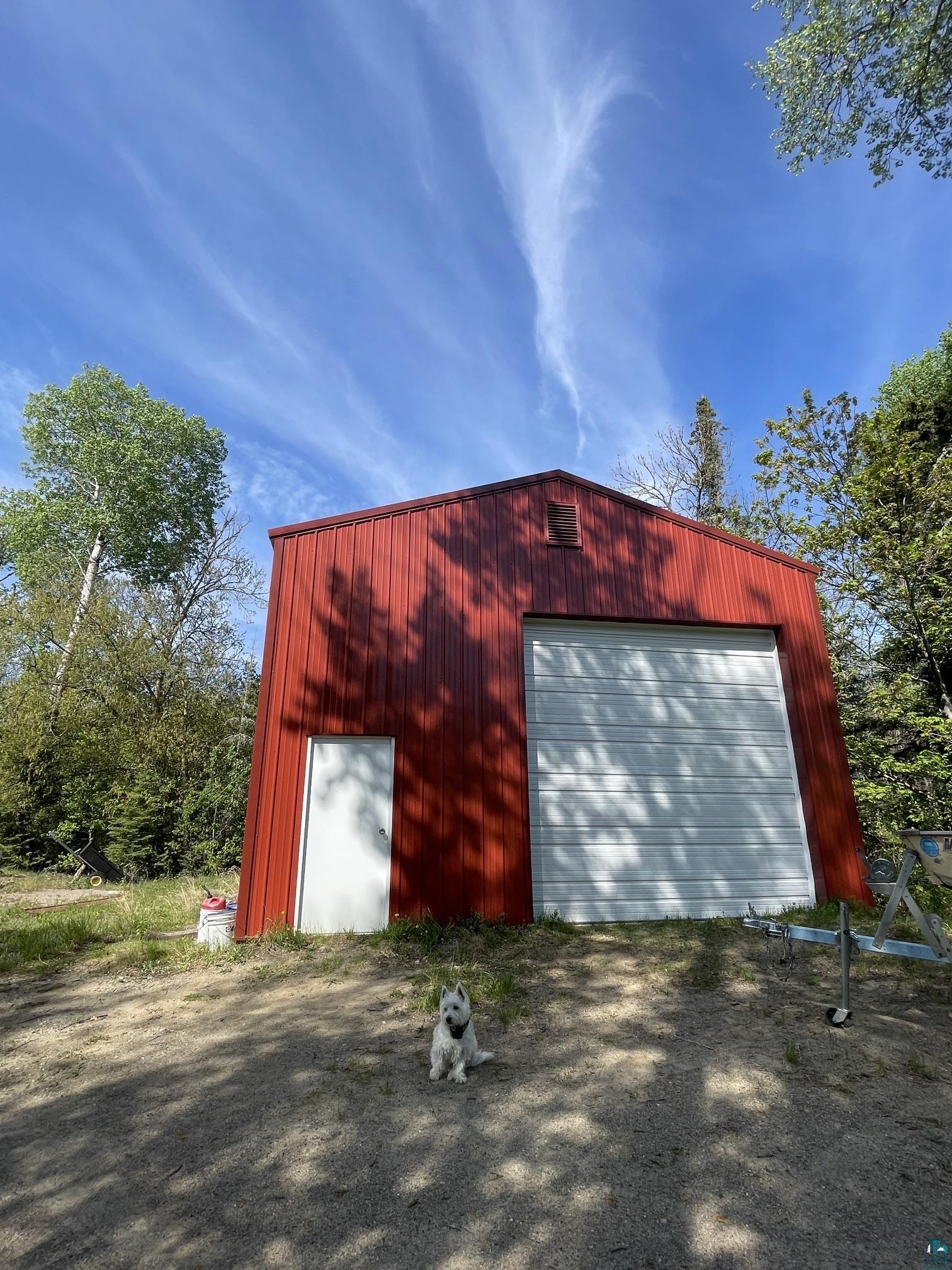 1152 Fernberg Road Ely, MN 55731 - Photo 18 of 24 Red metal utility building featuring a white side entry door and a large white overhead garage door