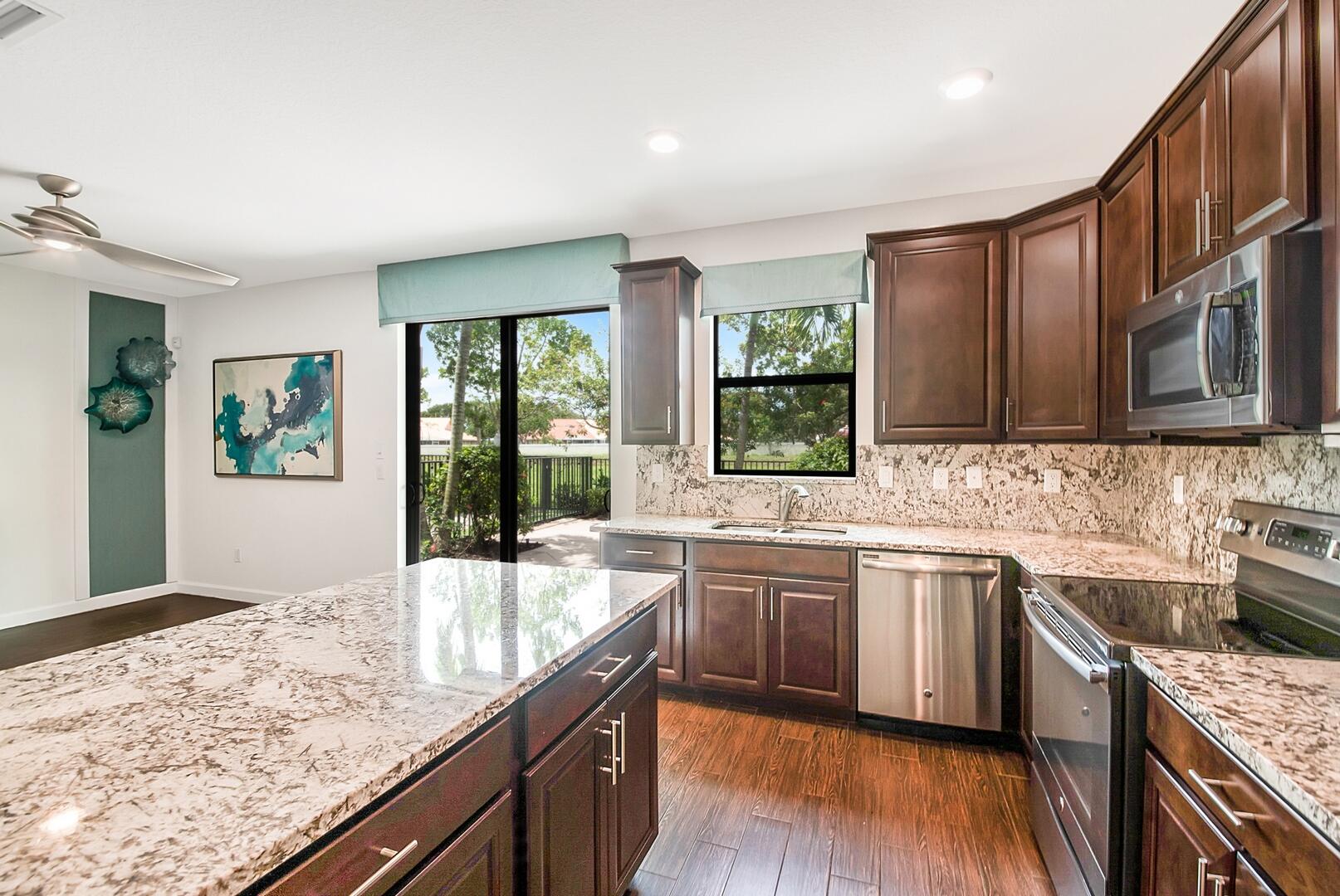 13076 Anthorne Lane Boynton Beach, FL 33436 - Photo 10 of 36 a kitchen with stainless steel appliances granite countertop wooden cabinets a sink dishwasher a stove and a refrigerator with wooden floor