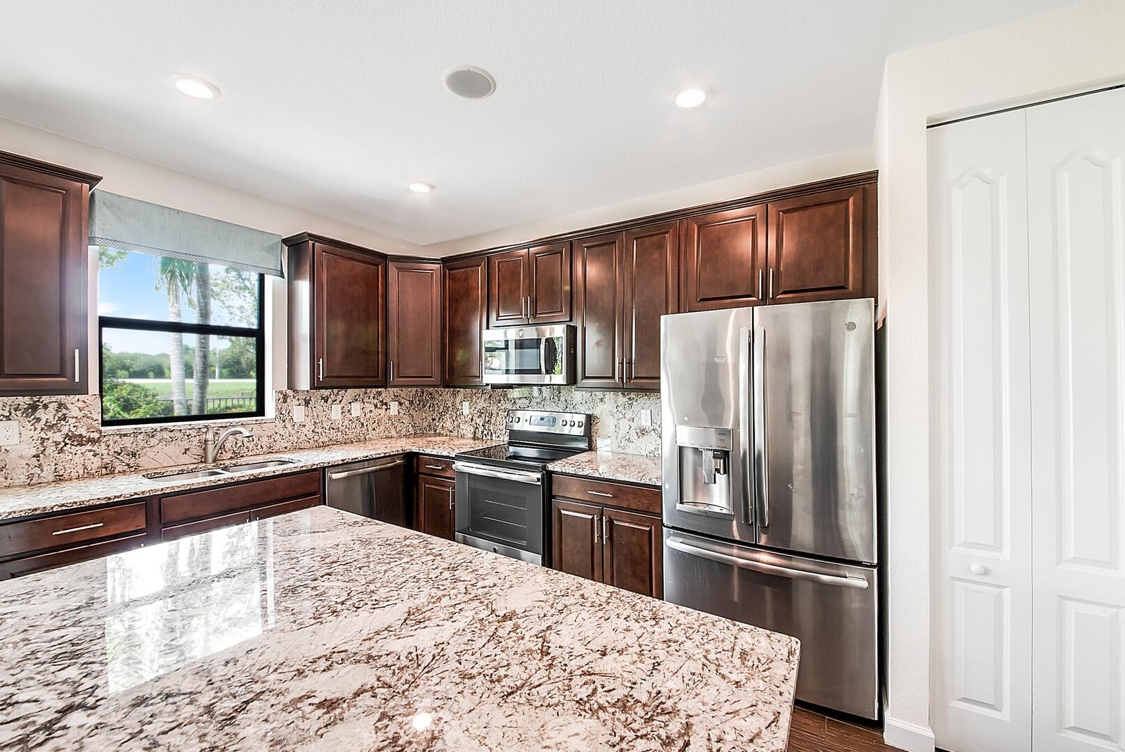 13076 Anthorne Lane Boynton Beach, FL 33436 - Photo 11 of 36 a kitchen with granite countertop stainless steel appliances and wooden cabinets