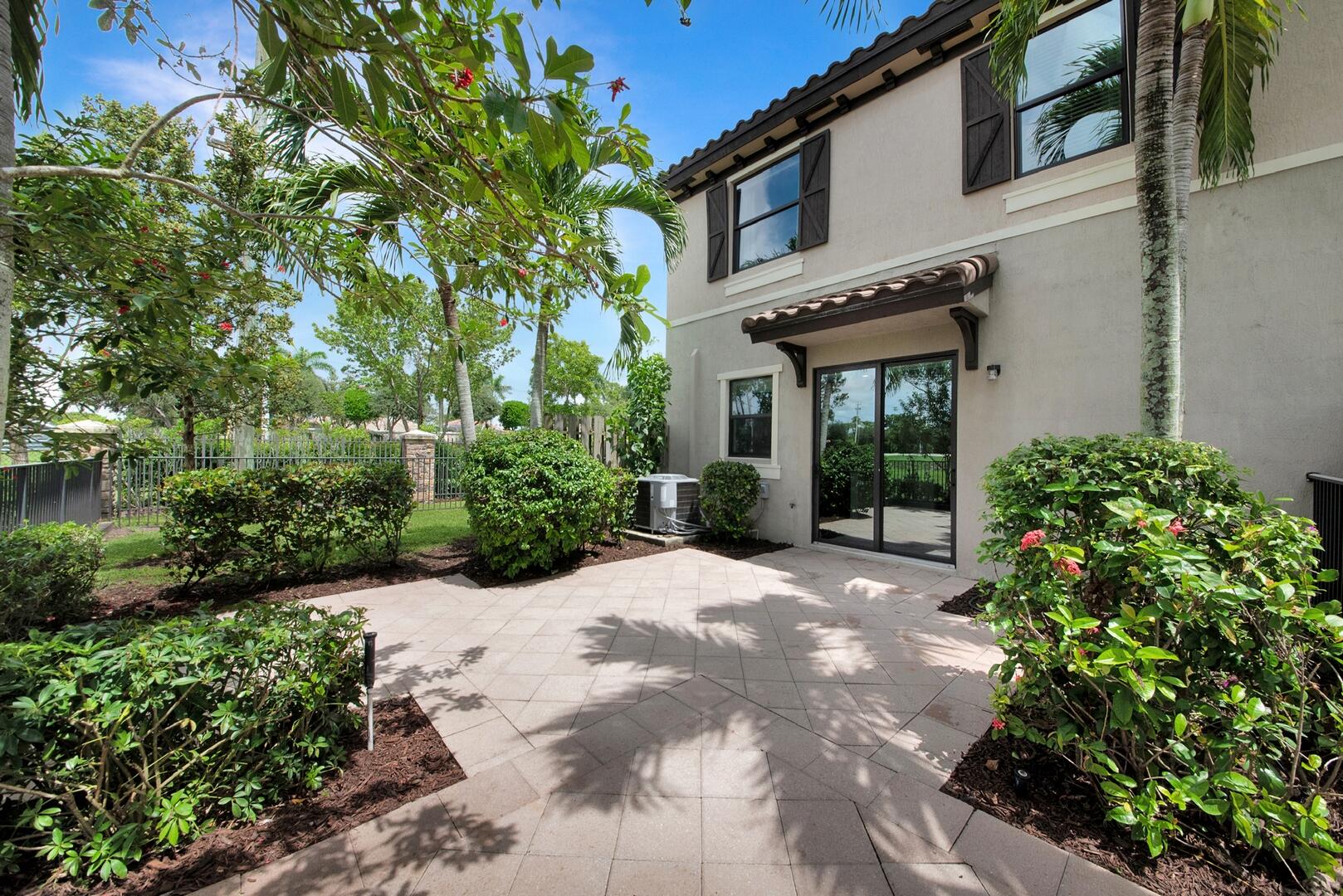 13076 Anthorne Lane Boynton Beach, FL 33436 - Photo 23 of 36 a view of a house with potted plants and a large tree