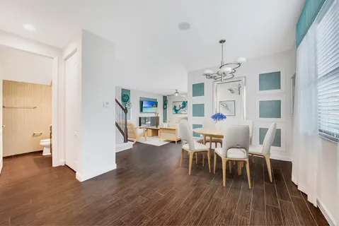 a dining room with wooden floor a chandelier a glass table and chairs