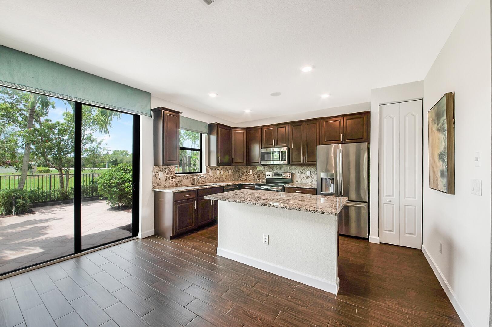 13076 Anthorne Lane Boynton Beach, FL 33436 - Photo 7 of 36 a kitchen with stainless steel appliances granite countertop a refrigerator a sink dishwasher a stove and white countertops with wooden floor