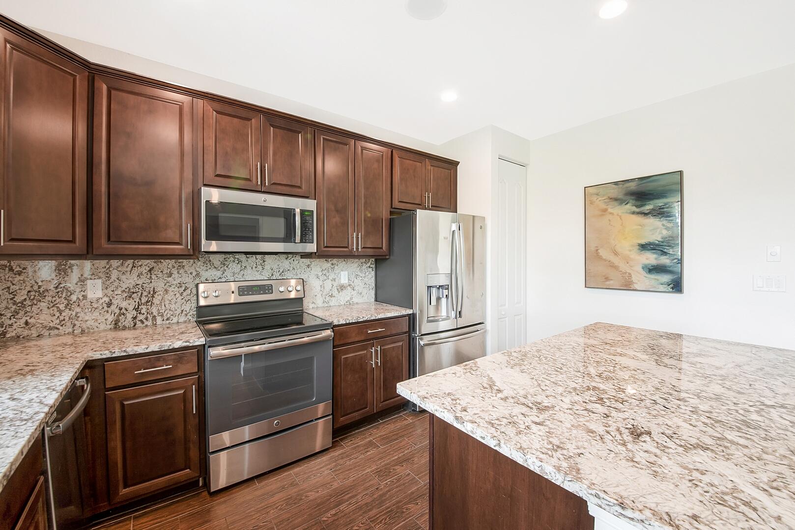 13076 Anthorne Lane Boynton Beach, FL 33436 - Photo 8 of 36 a kitchen with stainless steel appliances granite countertop a stove refrigerator and microwave