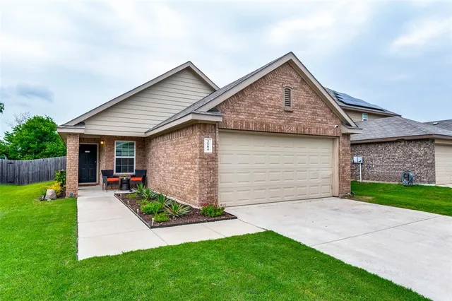 a view of a house with a yard plants and a large tree