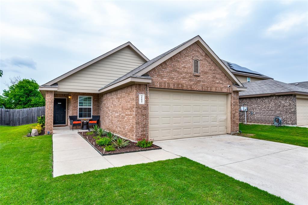 a view of a house with a yard plants and a large tree