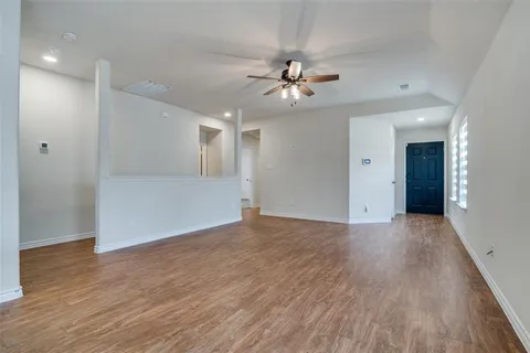 a view of empty room with wooden floor and ceiling fan