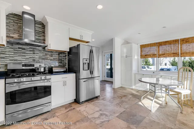 a kitchen with stainless steel appliances granite countertop a stove a sink dishwasher a refrigerator white cabinets and wooden floor