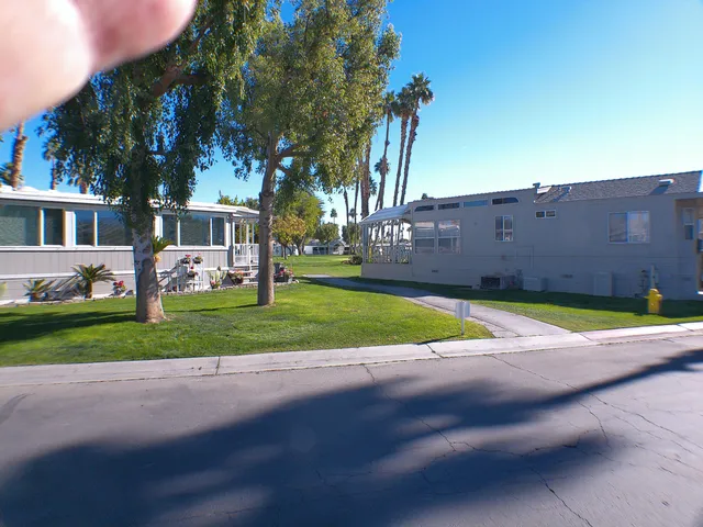 a view of a house with a big yard and palm trees