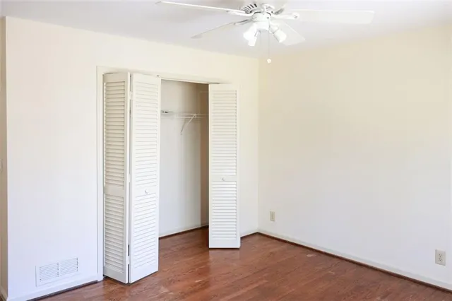 an empty room with wooden floor and fan