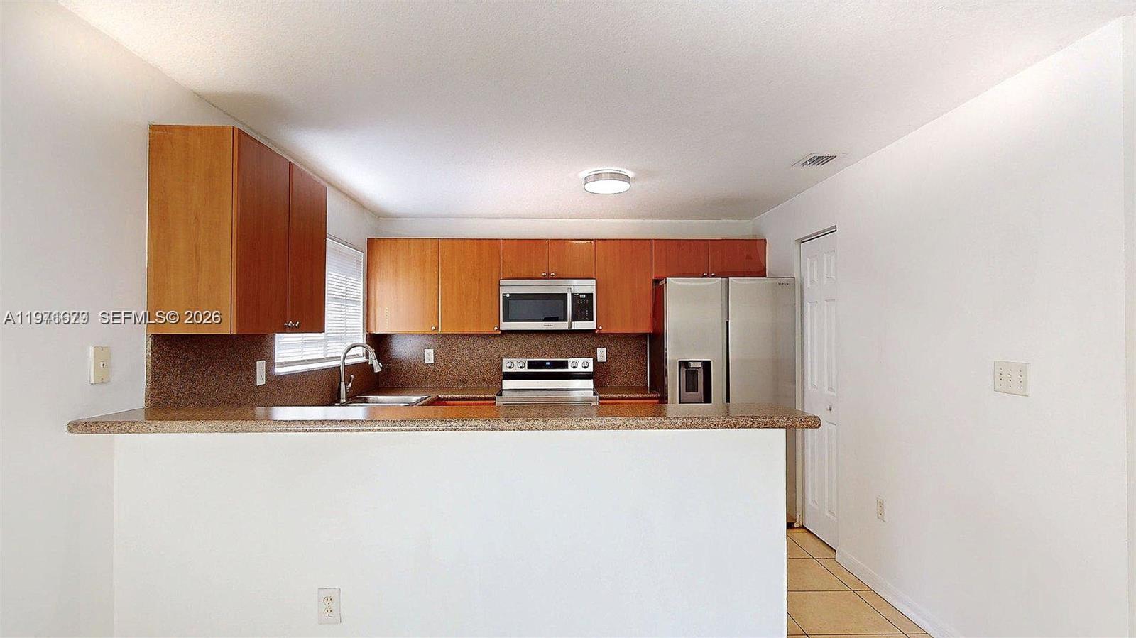 14162 Southwest 260th Street, Unit 104 Homestead, FL 33032 - Photo 11 of 35 a kitchen with stainless steel appliances granite countertop a sink and a refrigerator