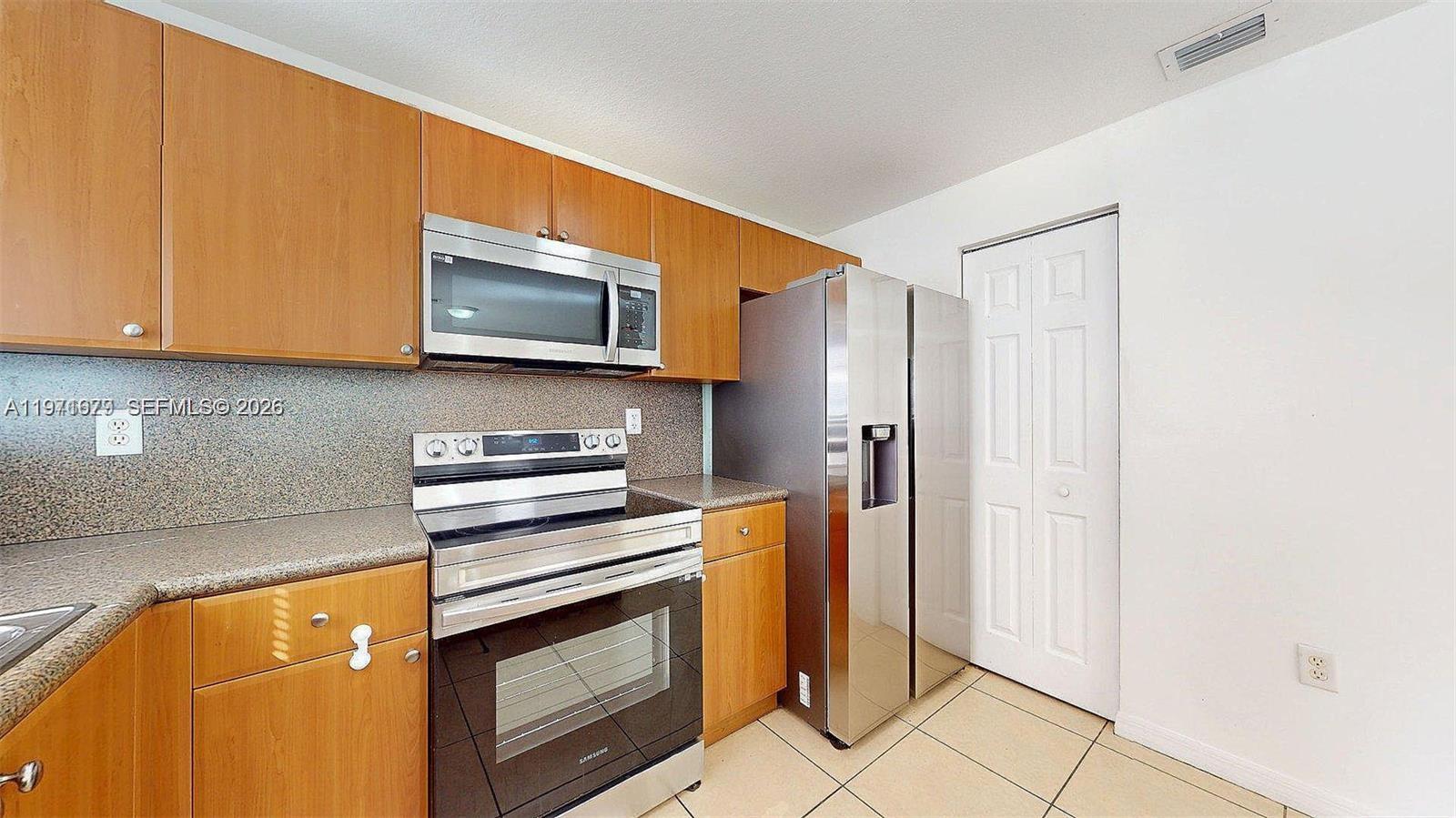 14162 Southwest 260th Street, Unit 104 Homestead, FL 33032 - Photo 13 of 35 a kitchen with stainless steel appliances granite countertop a stove microwave and refrigerator