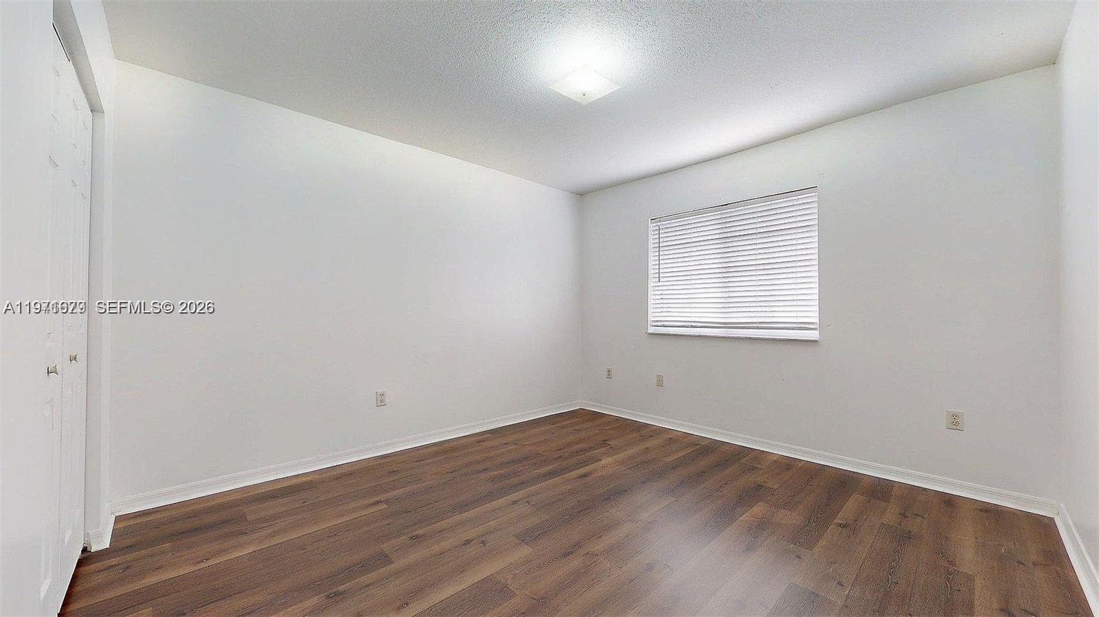 14162 Southwest 260th Street, Unit 104 Homestead, FL 33032 - Photo 27 of 35 an empty room with wooden floor and windows