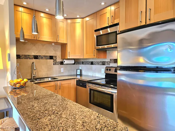 a kitchen with stainless steel appliances granite countertop a sink stove and refrigerator