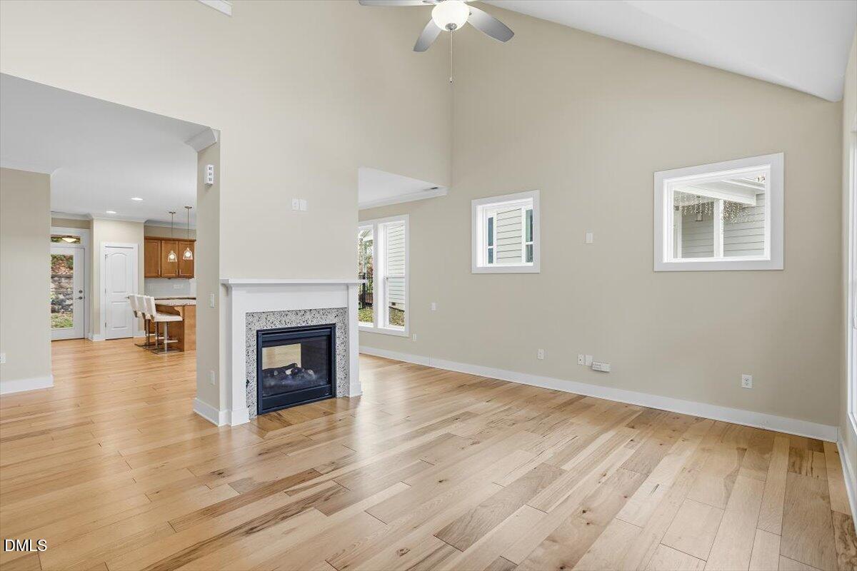 4409 Spiedie Court Raleigh, NC 27606 - Photo 10 of 33 an empty room with wooden floor a fireplace and windows