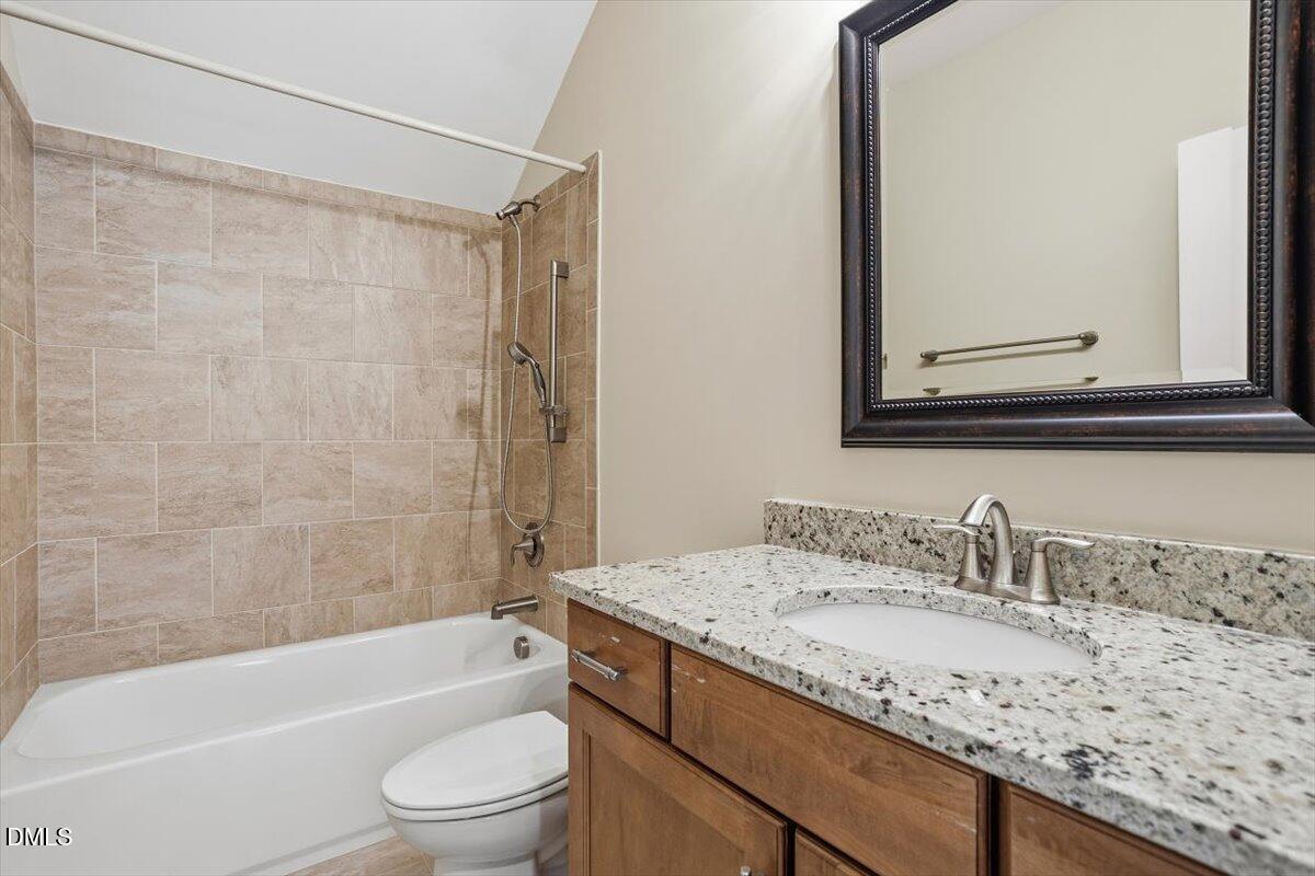 4409 Spiedie Court Raleigh, NC 27606 - Photo 24 of 33 a bathroom with a granite countertop sink a toilet and bathtub