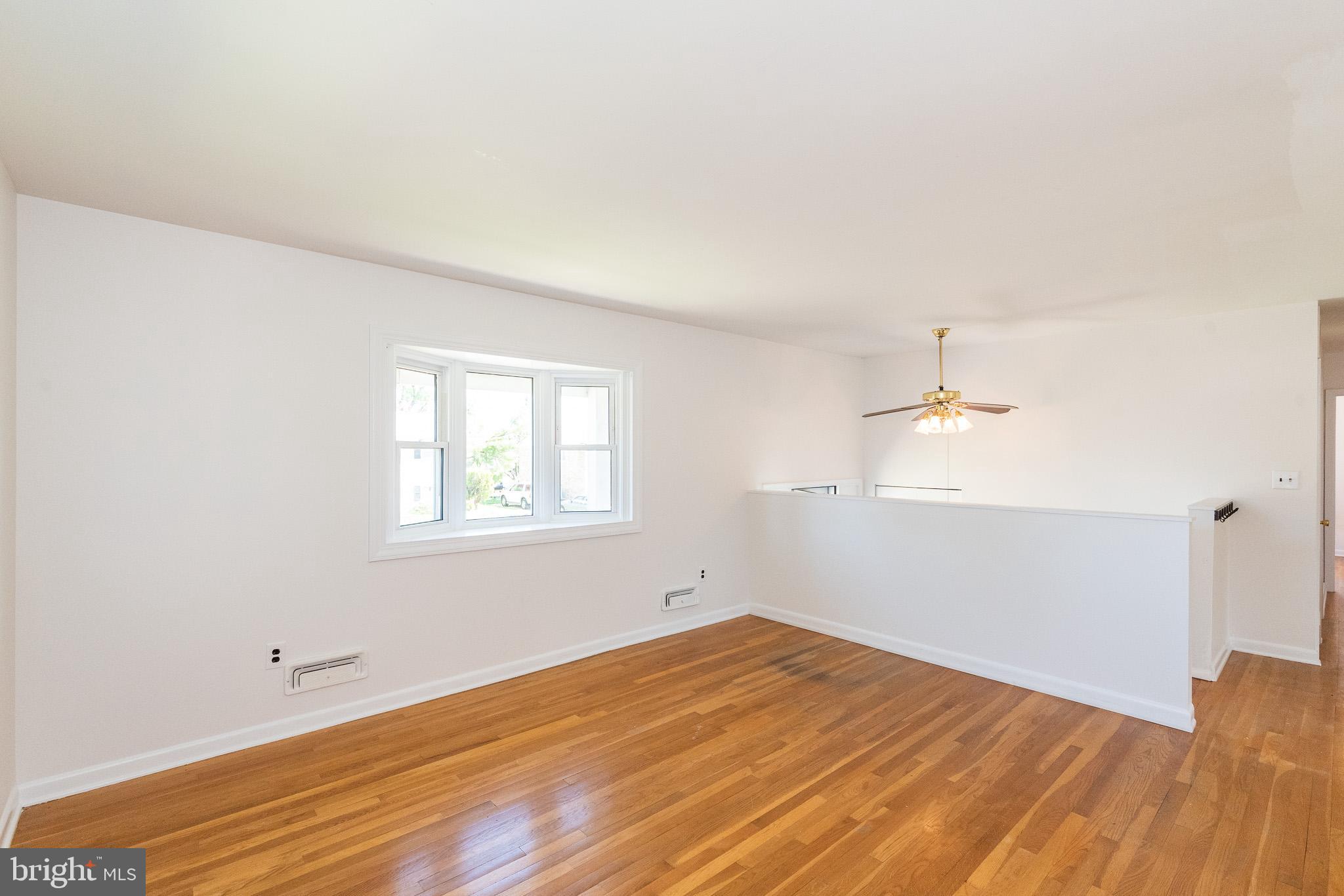 6129 Wheatland Road Baltimore, MD 21228 - Photo 12 of 48 an empty room with wooden floor and windows