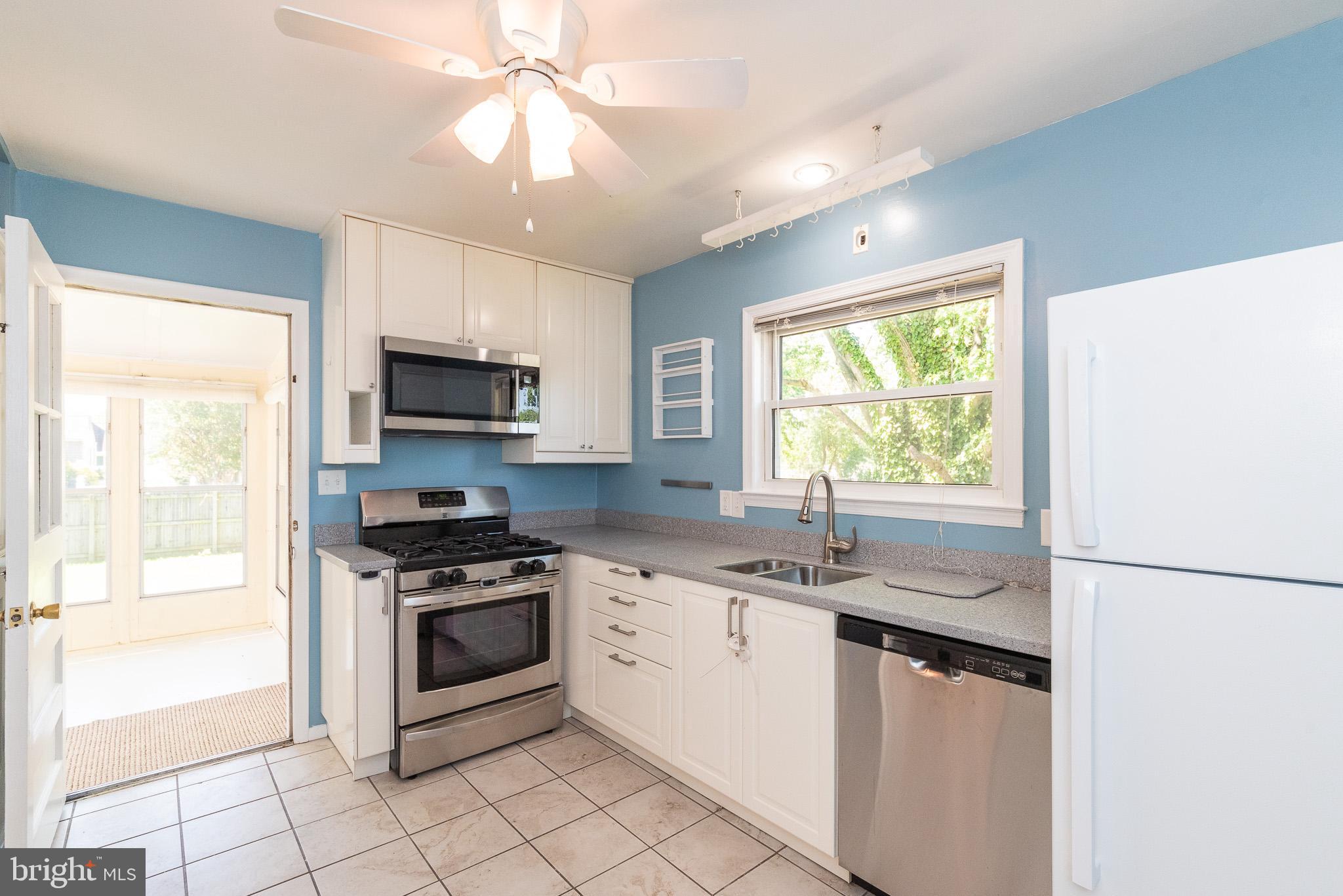 6129 Wheatland Road Baltimore, MD 21228 - Photo 7 of 48 a kitchen with stainless steel appliances granite countertop white cabinets a sink a stove a refrigerator and a microwave