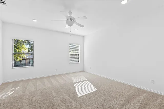 an empty room with windows and fan