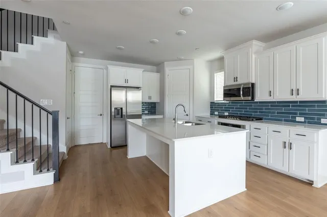 a kitchen with white cabinets sink and stainless steel appliances