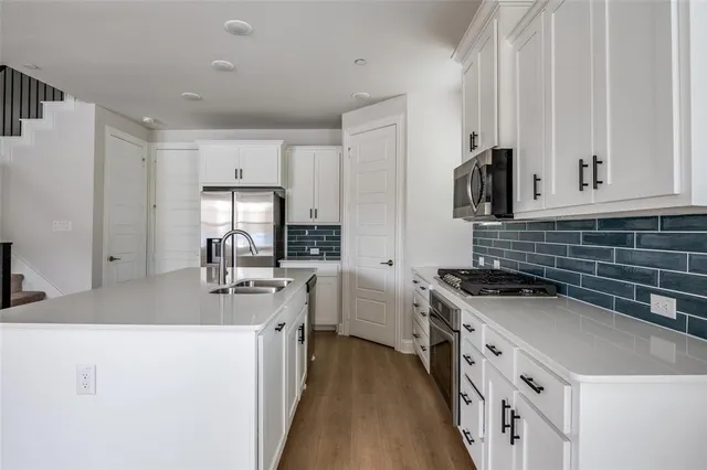 a kitchen with white cabinets sink and stove