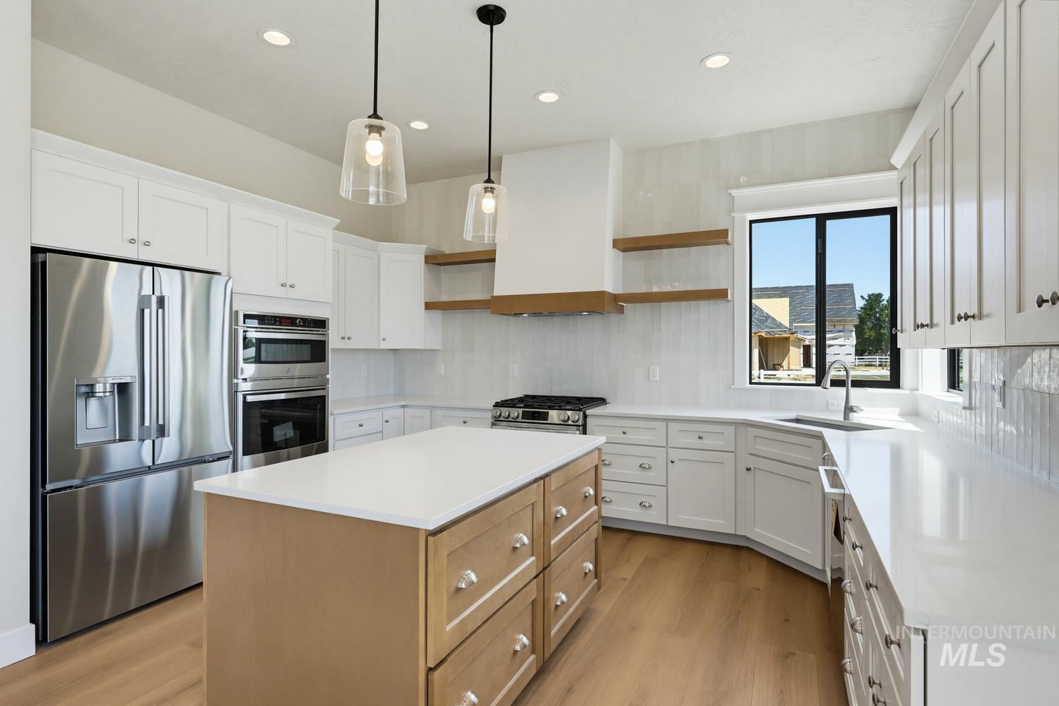 5054 Heritage Drive Marsing, ID 83639 - Photo 6 of 38 Gourmet kitchen featuring a central island with natural wood-finish cabinetry, white countertops, stainless steel appliances, and wood-finish flooring