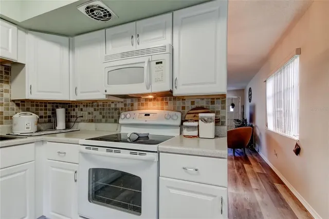 a kitchen with granite countertop white cabinets and white appliances