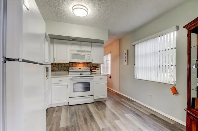a kitchen with a refrigerator and white cabinets