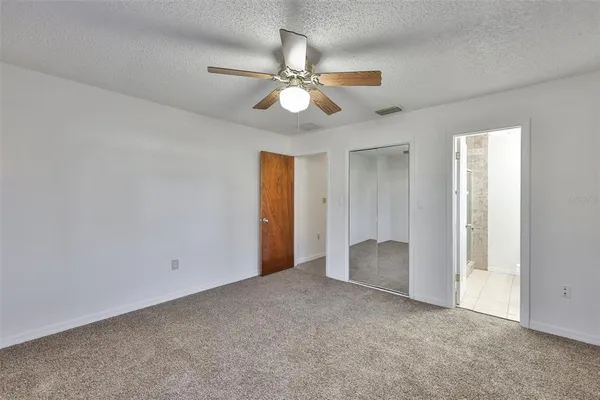 an empty room with closet and a chandelier fan