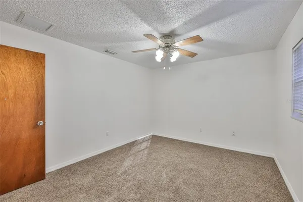 an empty room with a window and ceiling fan