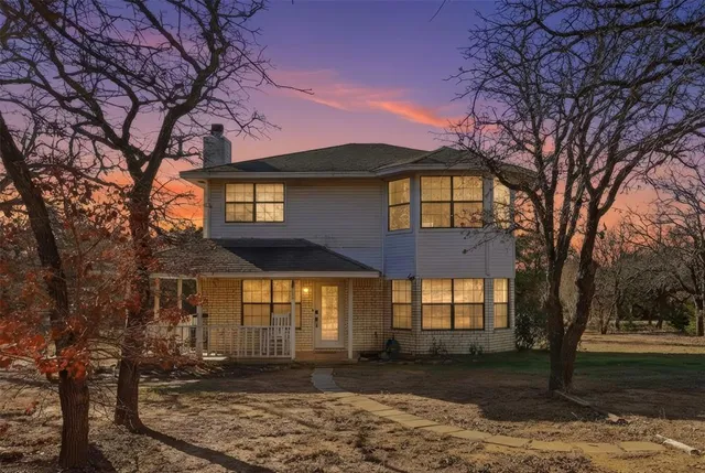 a front view of a house with large trees