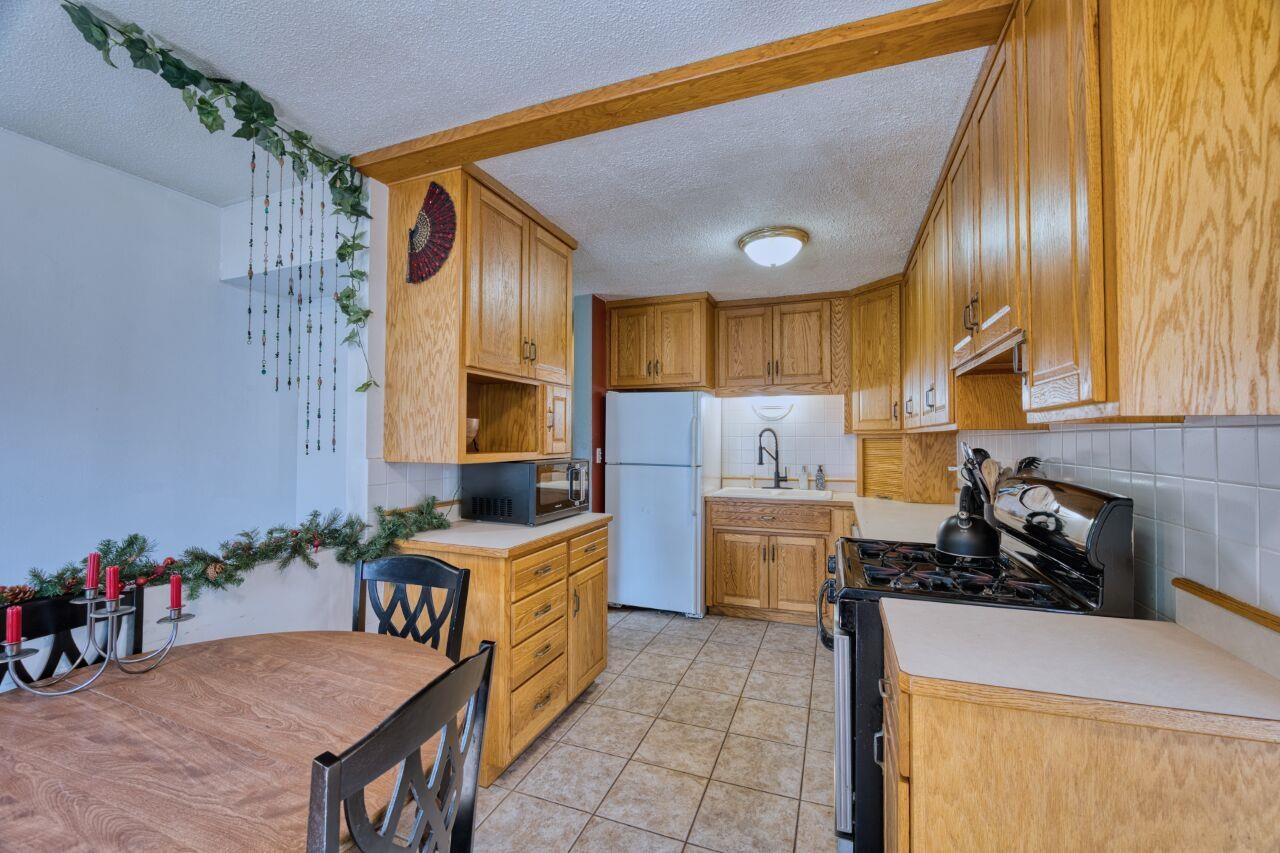 209 Brandon Road Hoyt Lakes, MN 55750 - Photo 6 of 38 Kitchen with black appliances, a textured ceiling, light countertops, tasteful backsplash, and open shelves