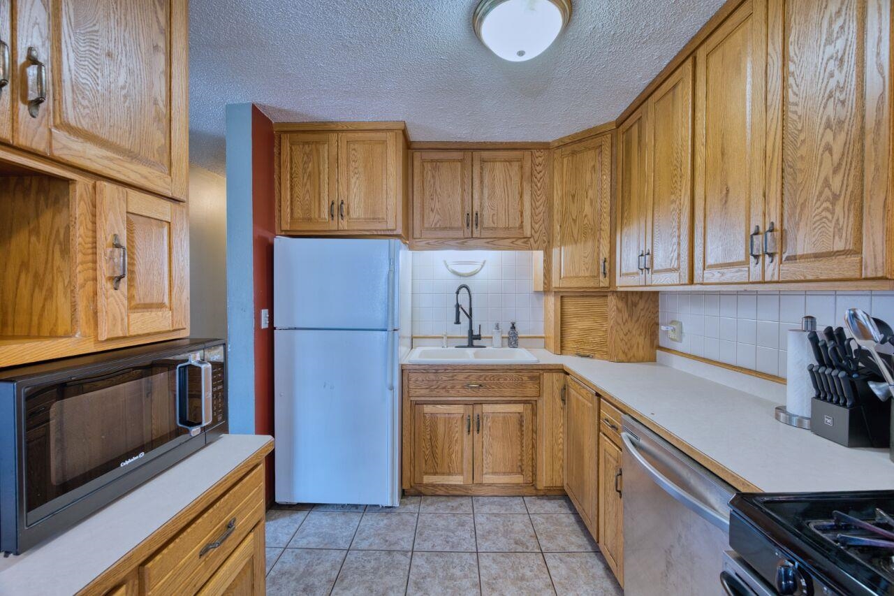 209 Brandon Road Hoyt Lakes, MN 55750 - Photo 8 of 38 Kitchen with freestanding refrigerator, black microwave, dishwasher, light countertops, and backsplash