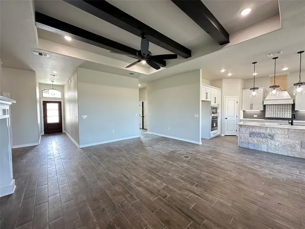 a view of a big room with wooden floor and a kitchen