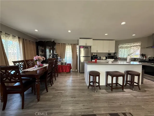 a kitchen with granite countertop a sink stove refrigerator and white cabinets with wooden floor