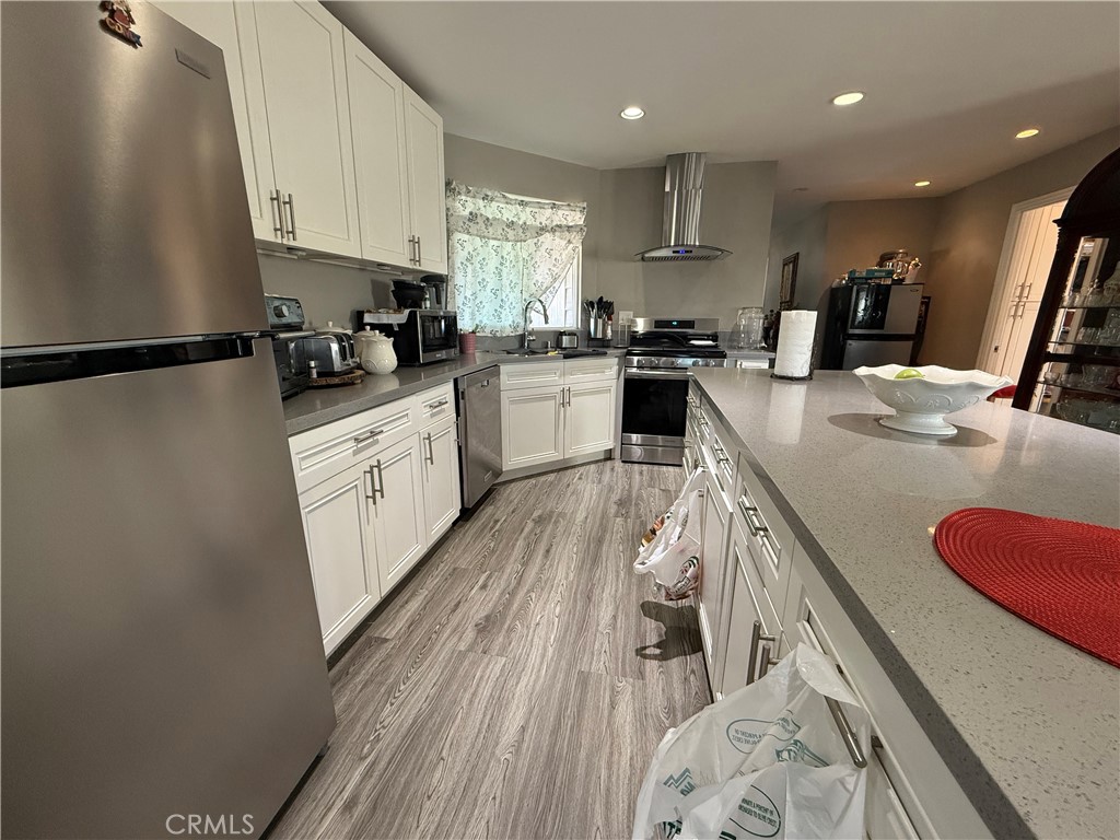2601 East Victoria Street, Unit 404 Compton, CA 90220 - Photo 14 of 30 a kitchen with granite countertop a sink stove refrigerator and white cabinets with wooden floor