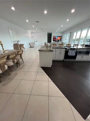 a living room with kitchen island furniture a kitchen view and a chandelier