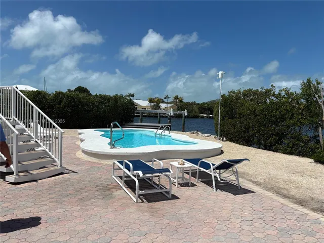 a swimming pool with outdoor seating and wooden fence