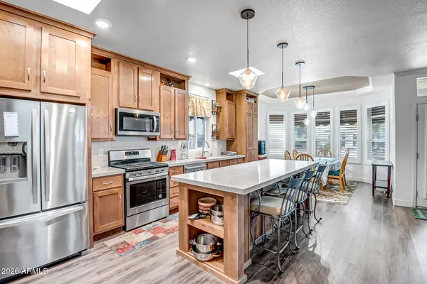 a kitchen with stainless steel appliances granite countertop a stove a refrigerator a oven a sink with a dining table and chairs