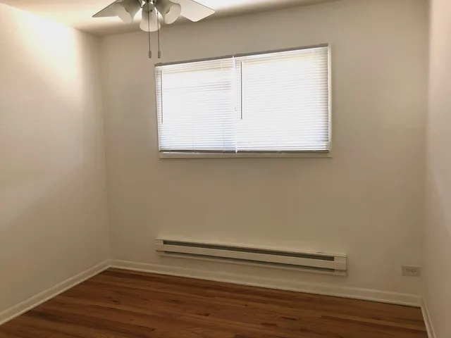 a view of a small space with wooden floor and fan