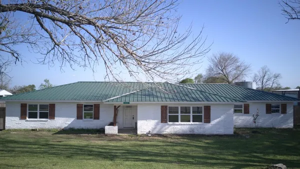 a front view of a house with a garden and trees