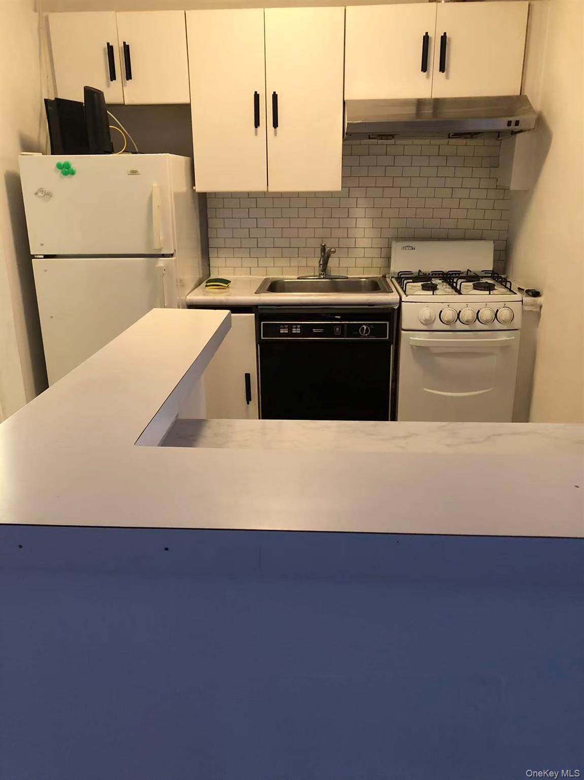 150-25 72nd Road, Unit 1L Queens, NY 11367 - Photo 8 of 12 a kitchen with a sink a stove and white cabinets
