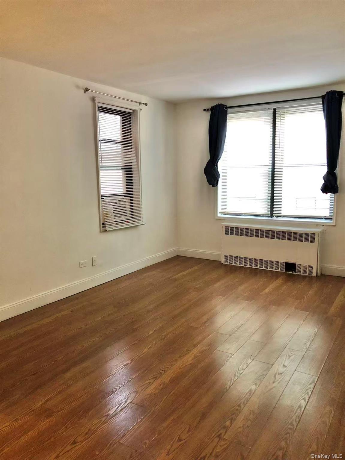 150-25 72nd Road, Unit 1L Queens, NY 11367 - Photo 10 of 12 a view of an empty room with wooden floor and a window