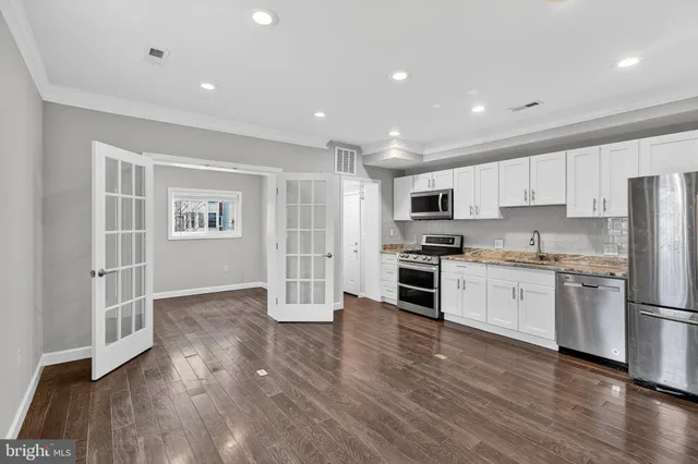 a kitchen with granite countertop a refrigerator oven a sink and dishwasher with wooden floor