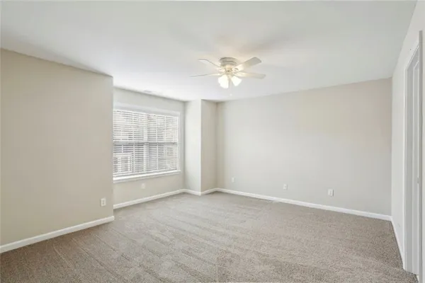 an empty room with chandelier fan and windows