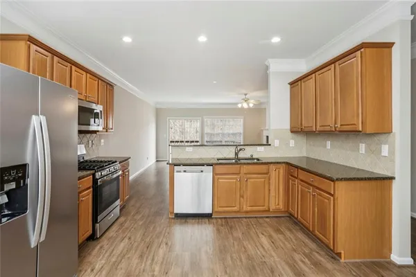 a kitchen with stainless steel appliances granite countertop a refrigerator a stove top oven a sink and dishwasher with wooden floor