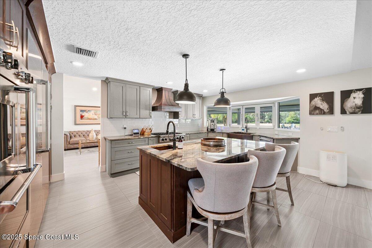 5685 Lake Washington Road Melbourne, FL 32934 - Photo 12 of 62 a kitchen with kitchen island granite countertop a table chairs microwave and cabinets