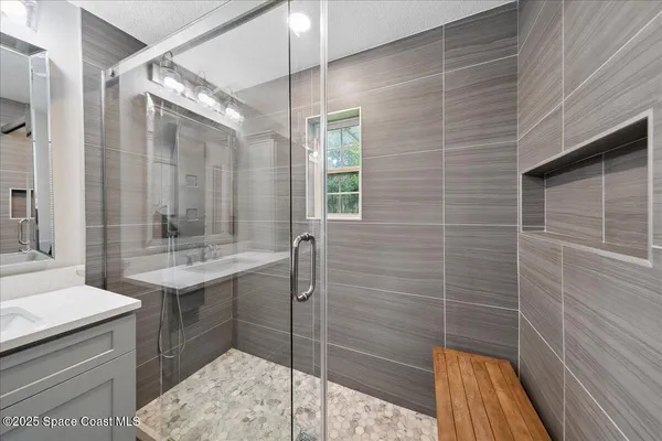 a bathroom with a sink shower and a mirror