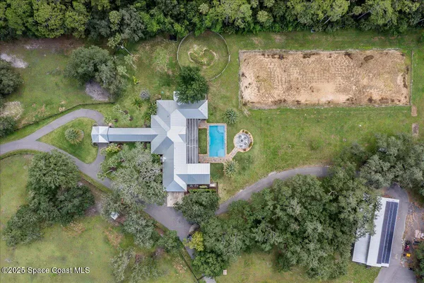 an aerial view of residential house with outdoor space and trees all around